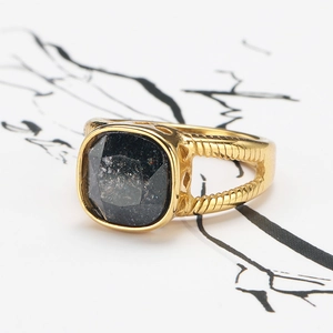 Vue macro d'une bague vintage dorée avec une pierre noire carrée et texture spirale