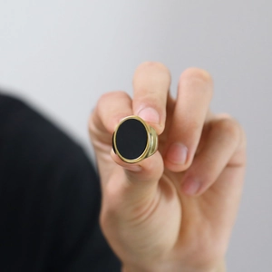 Detailaufnahme eines goldfarbenen Edelstahlrings mit mattem schwarzem Oval-Inlay
