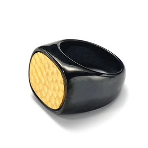 Detail eines schwarzen polierten Rings mit einer markanten goldfarbenen Hammerschlag-Optik