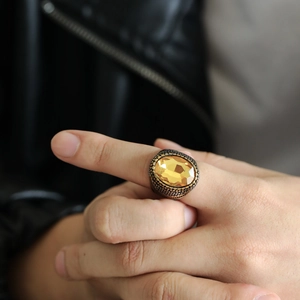 Detailaufnahme eines Vintage Herrenrings aus Edelstahl mit großem bernsteinfarbenem Stein