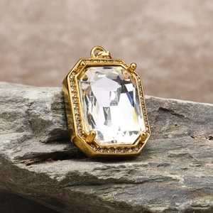 Macro detail of square emerald-cut crystal pendant on a natural stone background