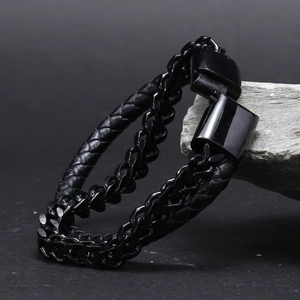 Close-up of black braided leather cord and metal curb chain bracelet with large clasp