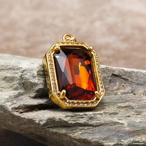 Detail of amber gemstone pendant with gold claw setting and pavé zircon border
