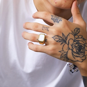 Detailed view of a gold square titanium ring with a white shell inlay on a model hand