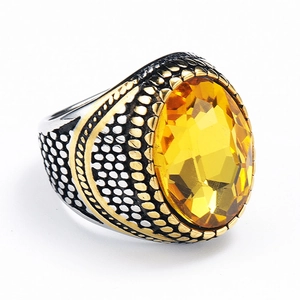 Makroaufnahme: Herrenring aus Edelstahl mit gelbem ovalem Edelstein und goldenen Mustern