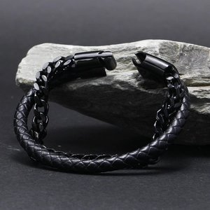 Detail of men's double-layer black chain and braided leather bracelet on rock