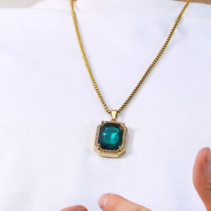 Detail of a square emerald pendant necklace with zirconia halo on a gold chain