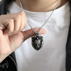 Detail of vintage steel shield pendant with warrior helmet relief worn by model