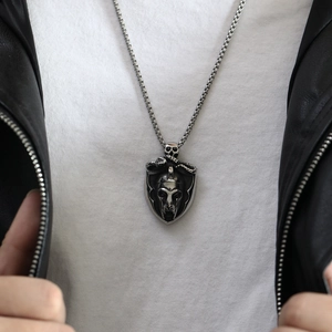 Close-up of vintage punk shield pendant with skull and warrior details on a box chain