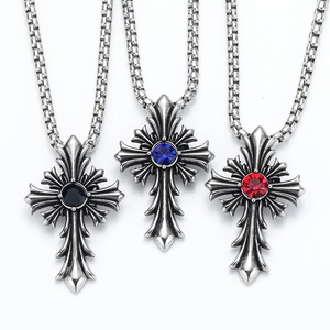 Detalle de tres colgantes de cruz gótica vintage con gemas negras, azules y rojas