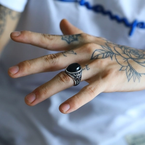 Dettaglio anello punk da uomo in acciaio con incisioni vintage e pietra di agata nera