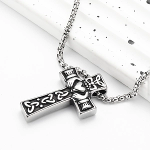 Dettaglio del cuore Claddagh e nodi celtici su una collana con croce in acciaio inox