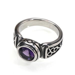 Macro shot of retro stainless steel ring featuring a purple faceted gemstone and carved motifs
