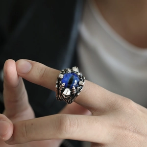 Macro detail of gothic punk ring featuring a blue eyeball held by dragon claws
