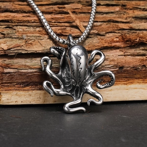 Close-up of vintage steel octopus pendant with textured engraving on tree bark background