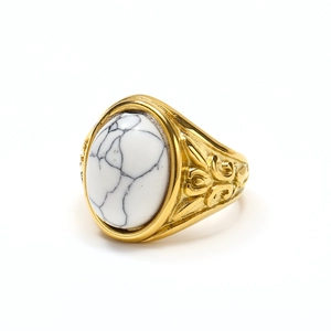Dettaglio macro di anello punk retrò dorato con pietra turchese bianca e incisioni