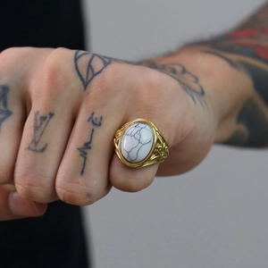 Dettaglio macro di un anello vintage da uomo in oro con marmo bianco e incisioni