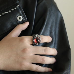Macro detail of gothic punk ring featuring red gemstone and silver dragon claw setting