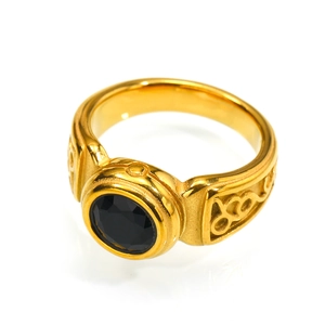 Macro shot of gold-plated ring with black gemstone and vintage floral engravings