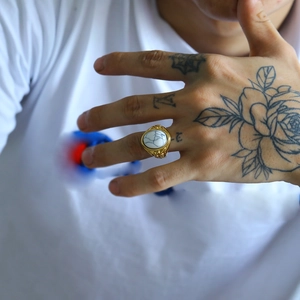 Dettaglio di un anello da uomo dorato vintage con intarsio in marmo bianco