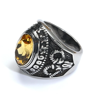 Primer plano del anillo punk de acero con gema amarilla ovalada y grabados de tótem