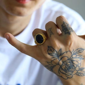 Dettaglio anello vintage da uomo in oro con grande pietra nera ovale e decori a sbalzo