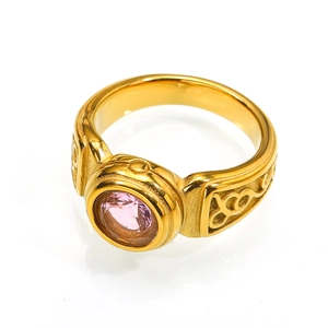 Detailed close-up of a gold titanium steel ring featuring a round pink gemstone inlay