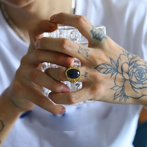 Dettaglio dell'anello punk vintage con pietra blu ovale e fascia dorata incisa sulla mano