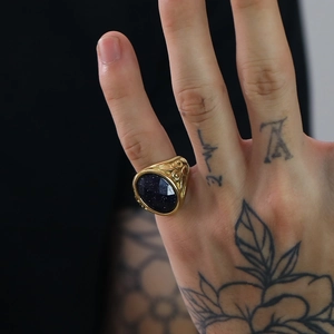 Dettaglio di un anello dorato vintage con pietra di sabbia blu e rilievo floreale
