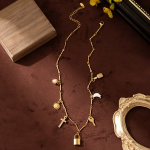 Gold plated stainless steel necklace with sun, moon, cross and pearl charms on velvet