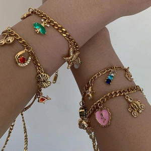 Dettaglio di bracciali dorati con ciondoli a forma di carrozza, stelle e cuori