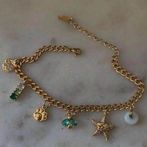 Macro di bracciale dorato con zirconi verdi e ciondoli a forma di zampa e stella