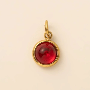 Vue rapprochée d'un pendentif rond plaqué or 18K avec une pierre cabochon rouge vif