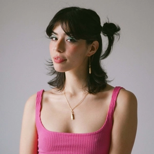 Detail of 18K gold-plated star pendant necklace and earrings on a model wearing pink