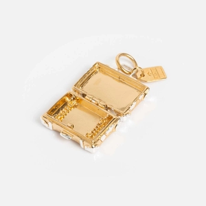 Détail macro du pendentif valise en métal doré avec étiquette FLIGHT gravée