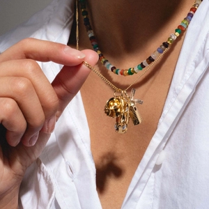 Détail du collier doré avec breloques moulin à vent et perles sur un modèle