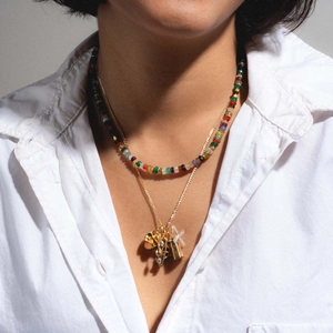 Gros plan d'un collier multicouche avec perles colorées et breloques musicales dorées