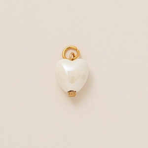 Detail eines weißen Keramik-Herzanhängers mit poliertem goldenem Ring auf strukturiertem Grund