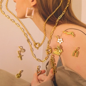 Gros plan de colliers dorés avec pendentifs papillon, cœur et bottes de cow-boy