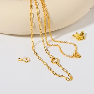 Détail de chaîne trombone et chaîne en O avec pendentifs papillon et fleur sur céramique
