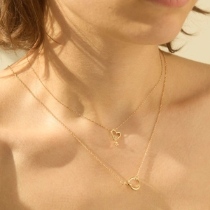 Close-up of layered gold heart and interlocking circle necklaces worn by a model