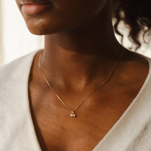 Élégant collier doré avec pendentif double pierre précieuse porté par un mannequin au cou