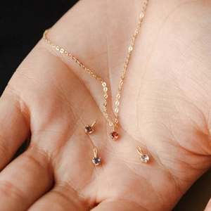 Détail d'un collier en chaîne dorée avec plusieurs pendentifs en pierres précieuses