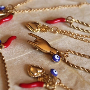 Golden Evil Eye and Cornicello necklaces displayed on vintage textured paper