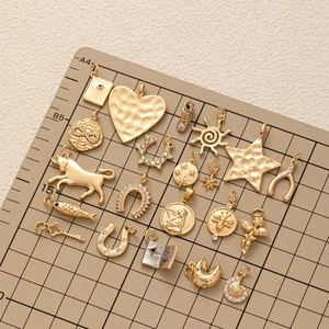 Ensemble de pendentifs dorés soleil, cœur et animaux disposés sur un support gradué