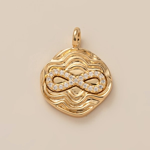 Macro d'un pendentif doré ondulé avec symbole de l'infini orné de cristaux brillants