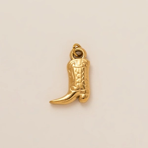 Detailed view of golden cowboy boot pendant with floral engraving and polished finish