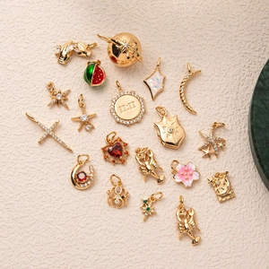 Various 18K gold plated brass charms with zircon inlay on a textured stone background