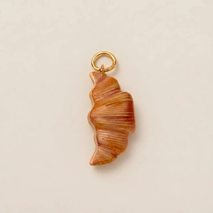 Macro detail of 3D croissant pendant with golden metal jump ring and realistic baked texture