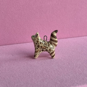 Detailed view of handmade ceramic cat pendant with brown leopard spots on cream glaze